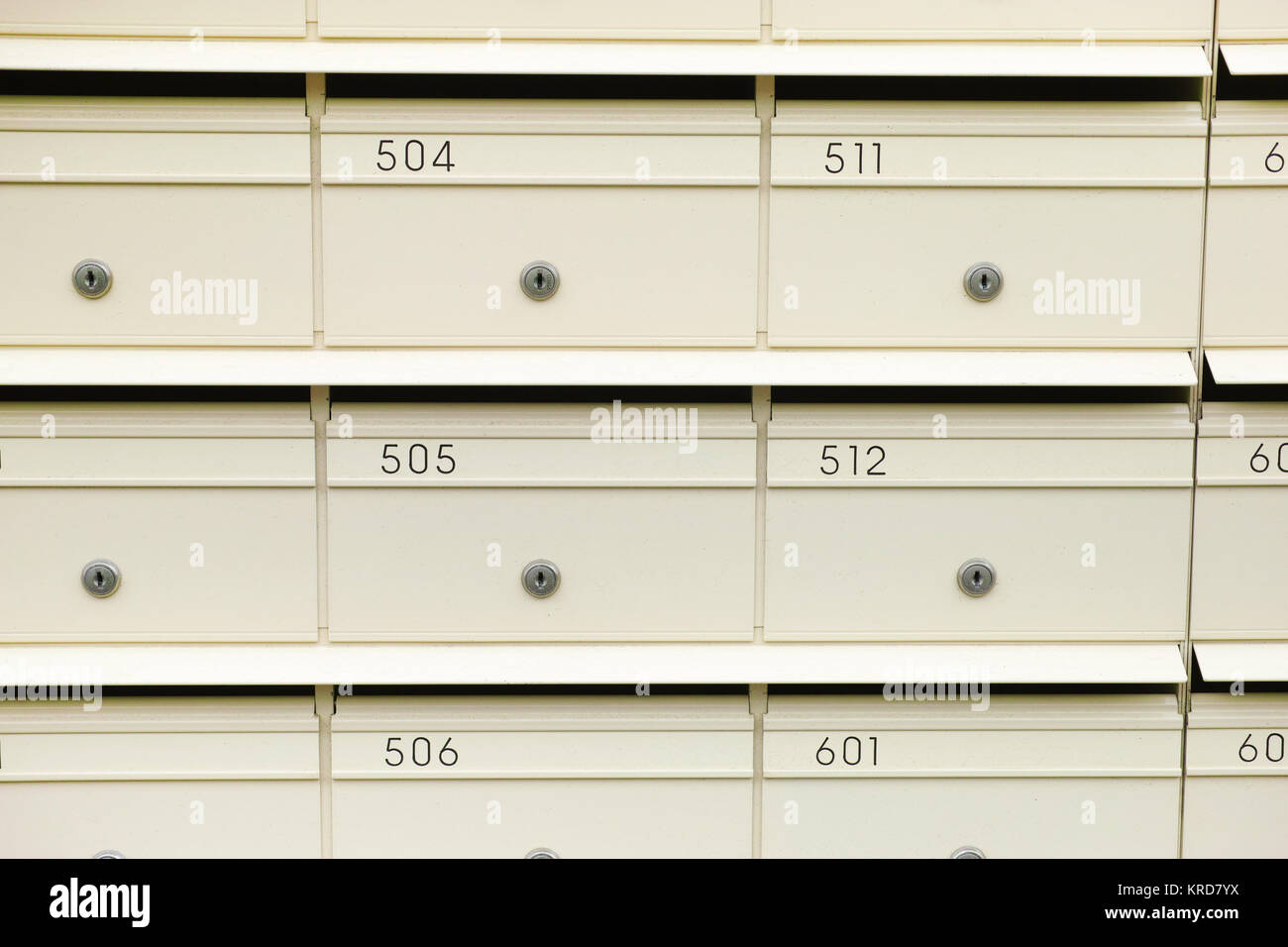 Close-up of a row of cream colored urban mailboxes with numbers, letter slots and individual locks. Letterboxes belonging to a block of flats in Sydne Stock Photo