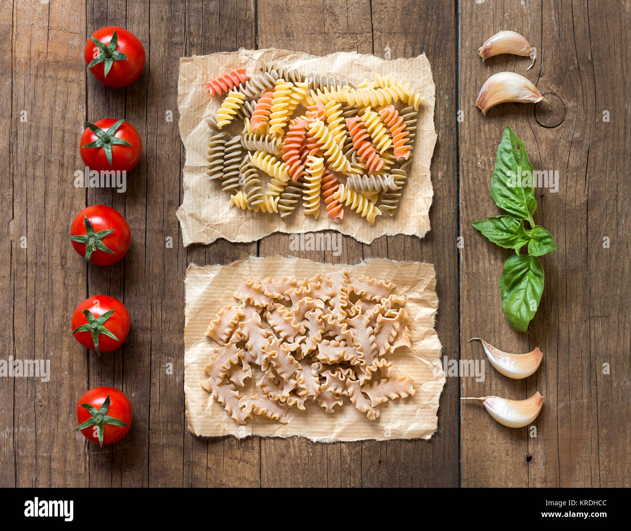 Pasta, pomodori, aglio e basilico sopra il tavolo di legno Stock Photo