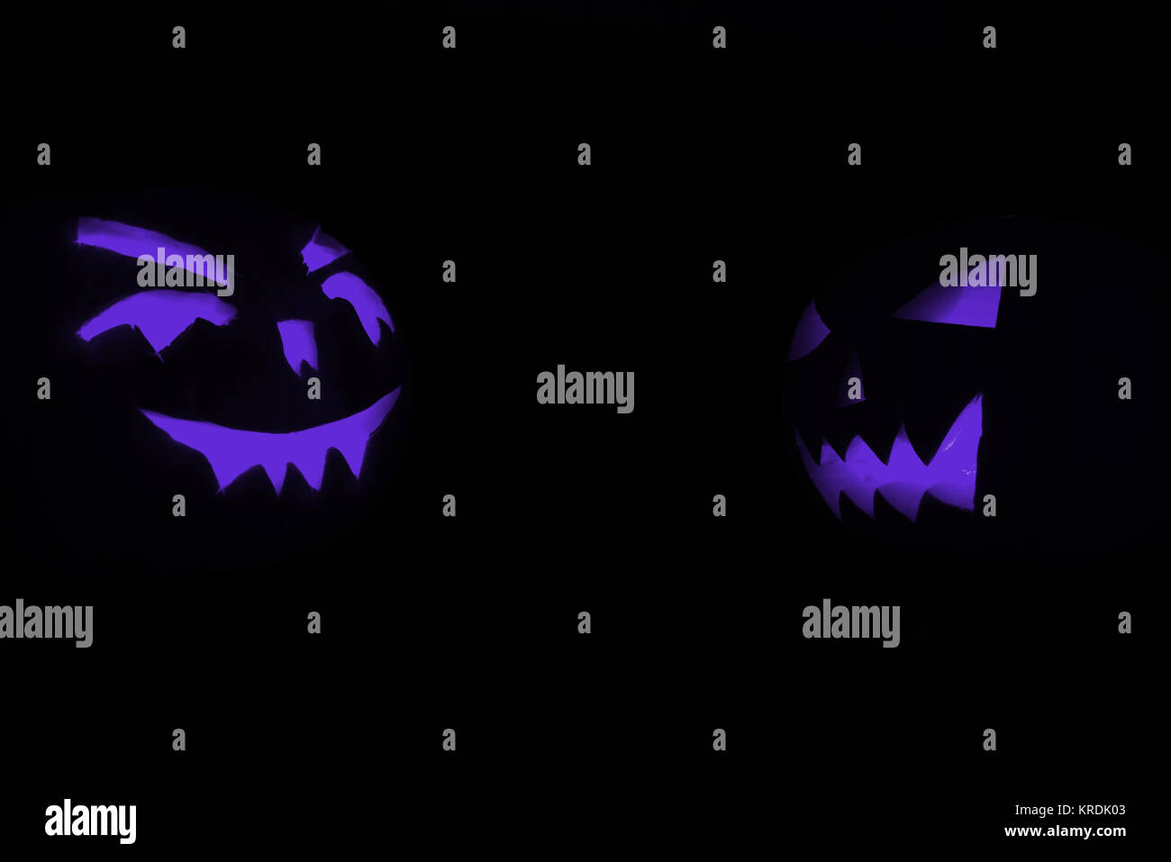 two blue carved face of pumpkin glowing on Halloween black background ...