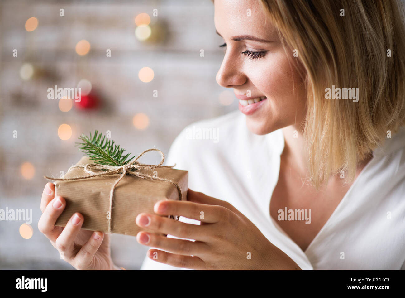 Young woman holding wrapped Christmas present Stock Photo - Alamy