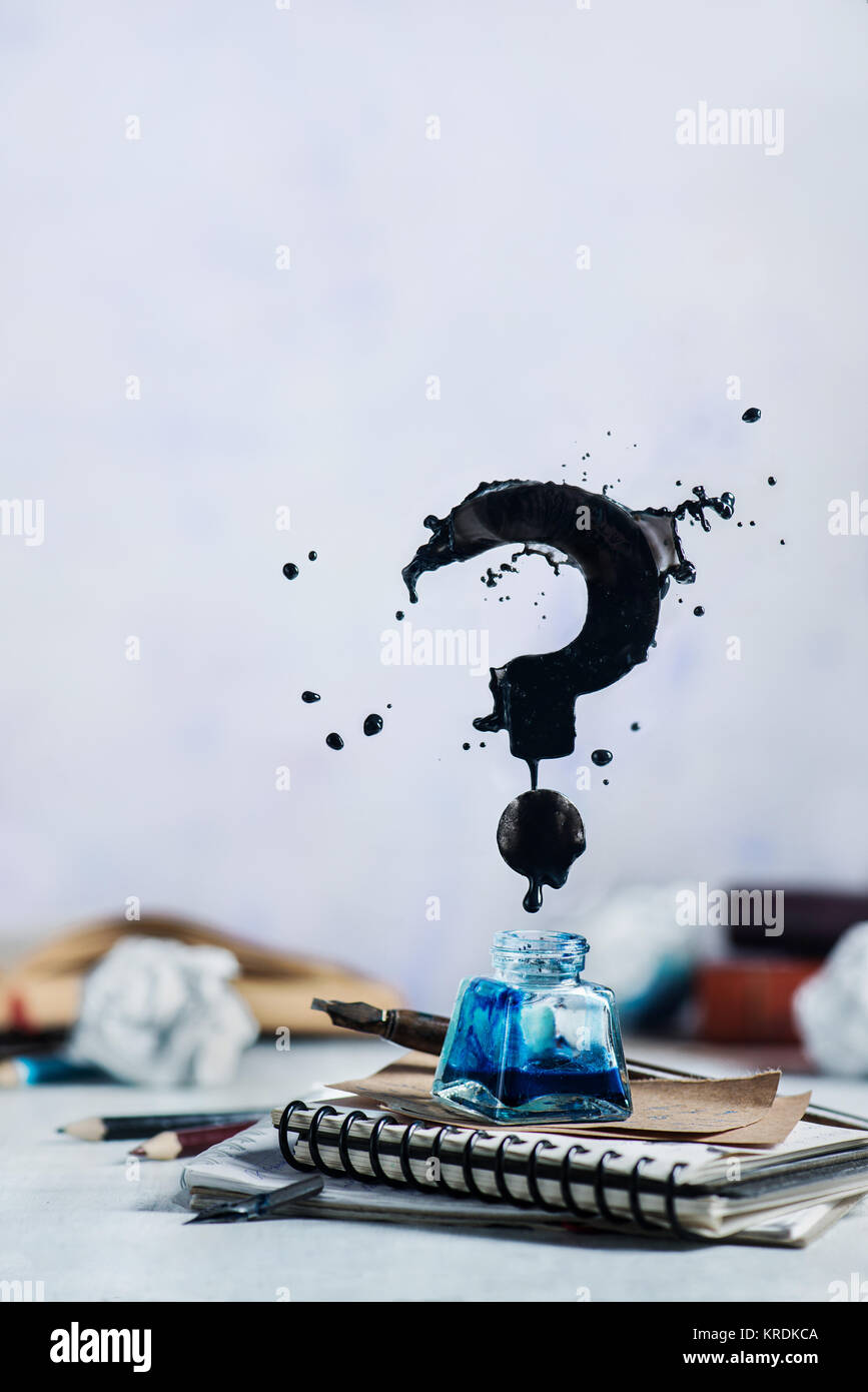 Spilled ink flying above inkwell in a splash in form of a question mark on a light background. Still life with writer workplace. Creative writing conc Stock Photo