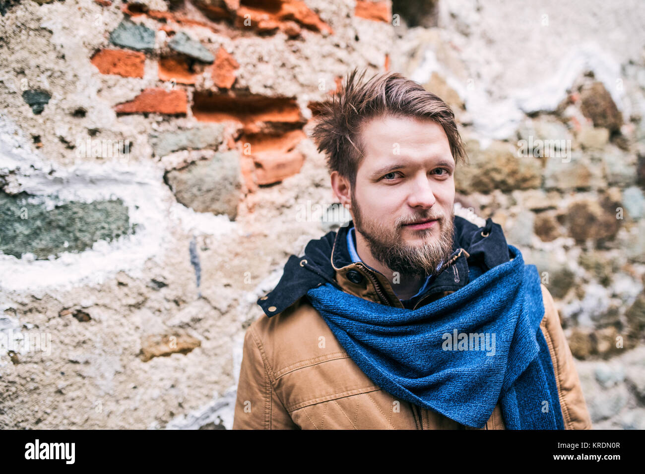 A young hipster man standing against an old brick wall. Stock Photo