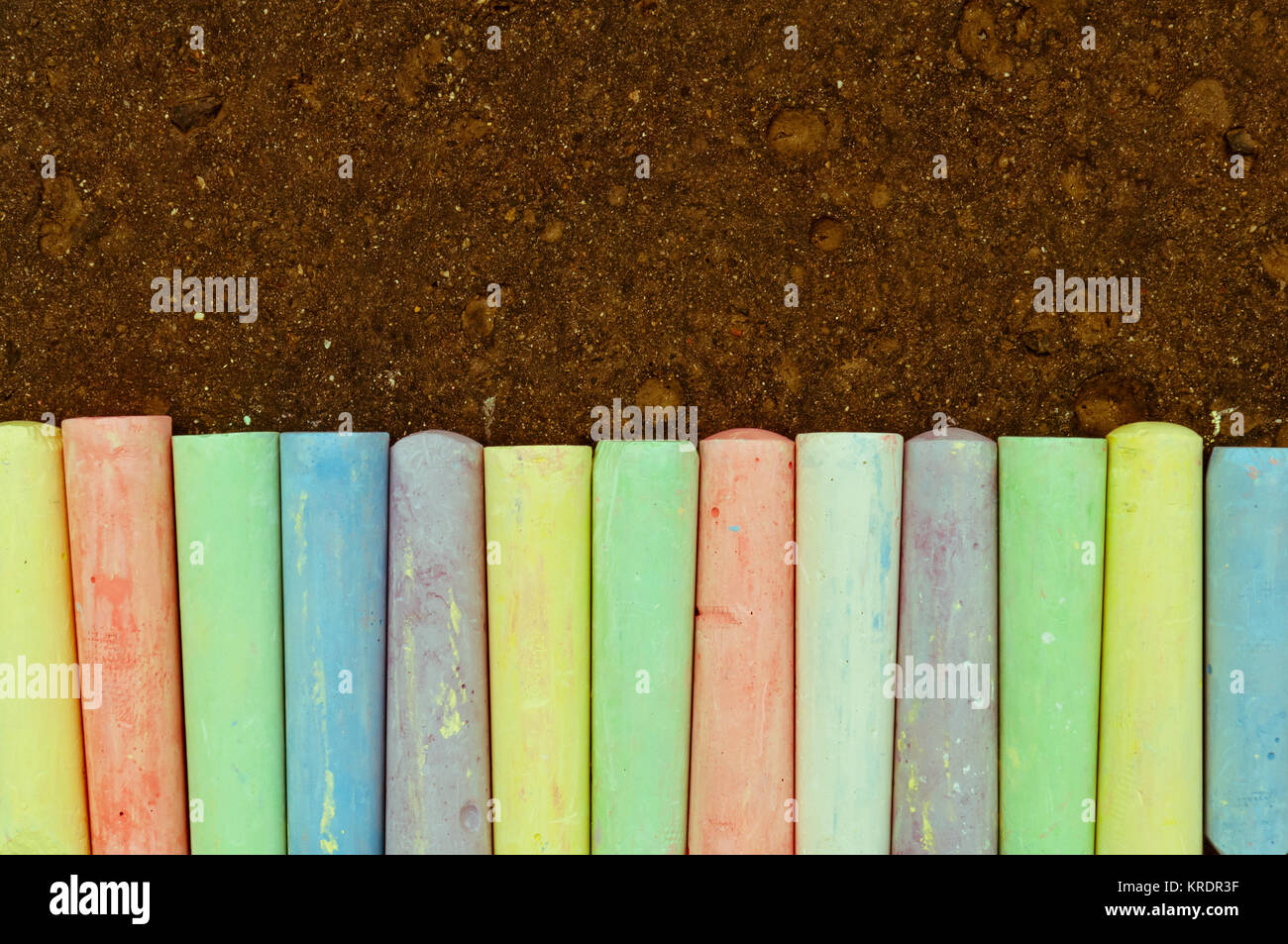 Colorful pastel sidewalk chalk on dark asphalt background Stock Photo