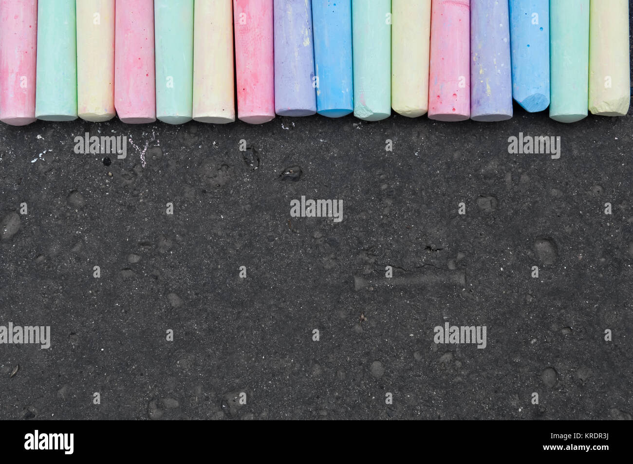 Colorful pastel sidewalk chalk on dark asphalt background Stock Photo