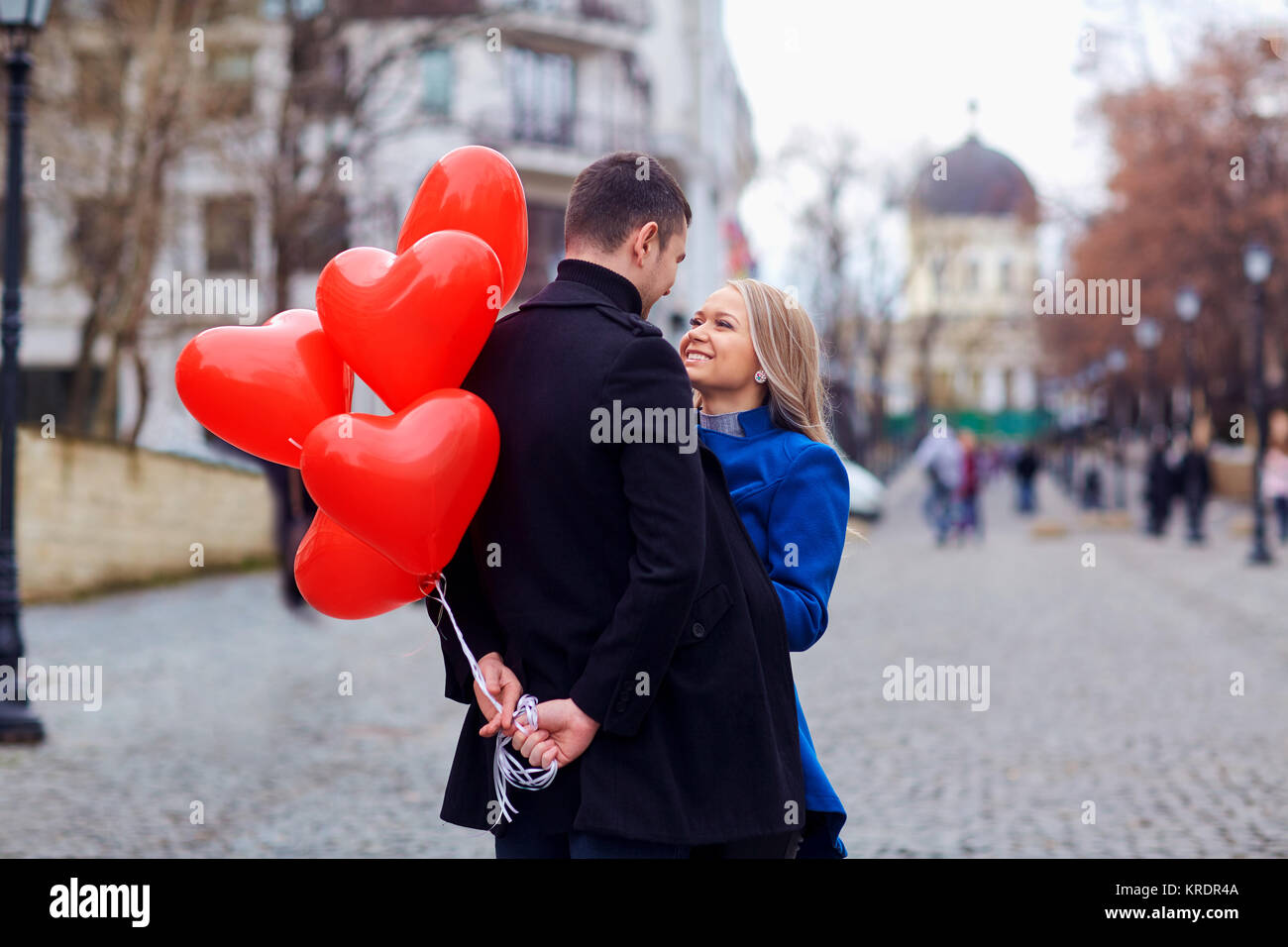 A loving couple with balloons hugs on a city street Stock Photo - Alamy