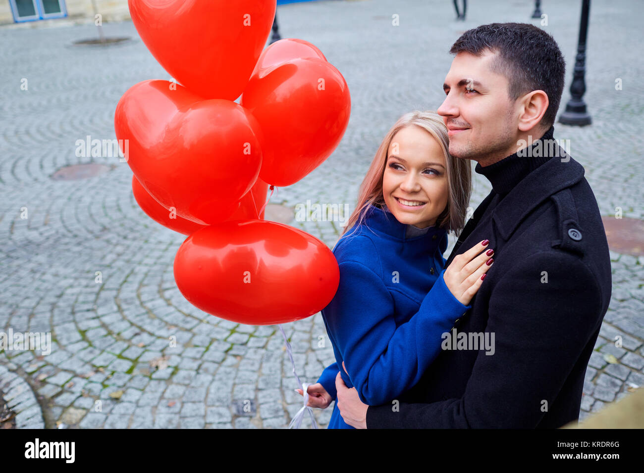 A loving couple with balloons hugs on a city street Stock Photo - Alamy