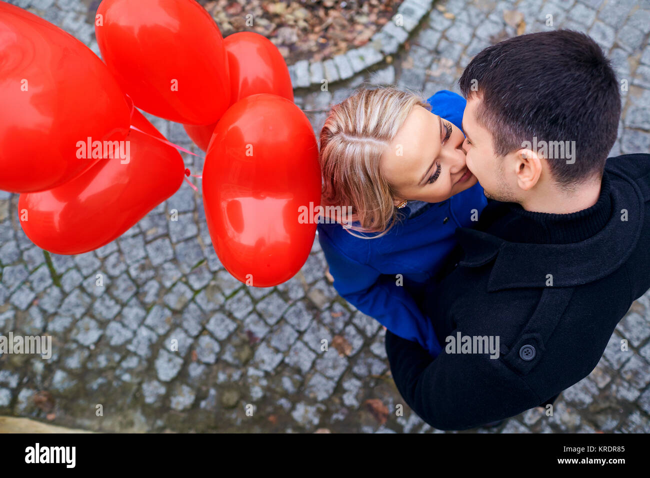 A loving couple with balloons kissing on a city street Stock Photo - Alamy