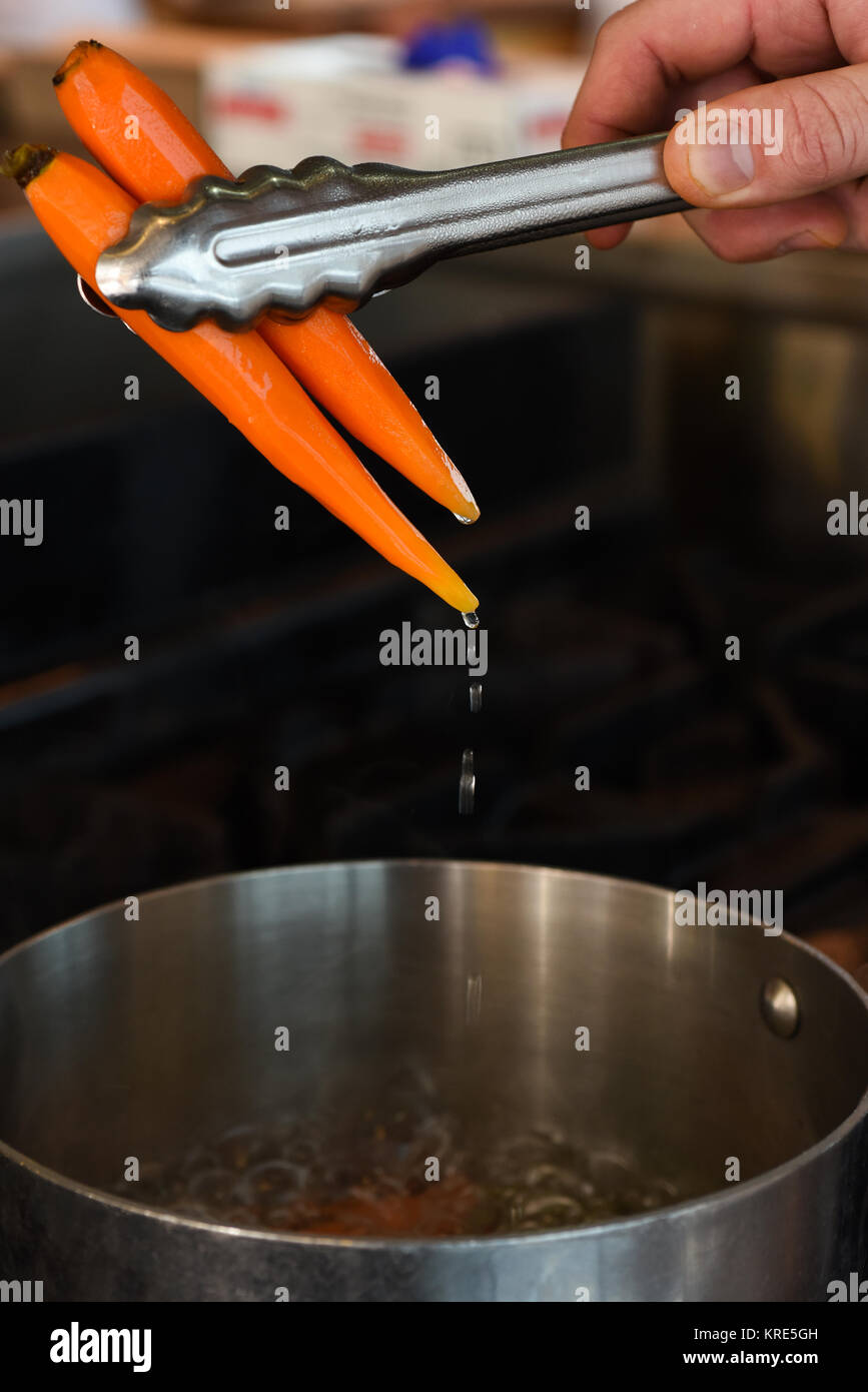 Carrots going into a pan of boiling water Stock Photo