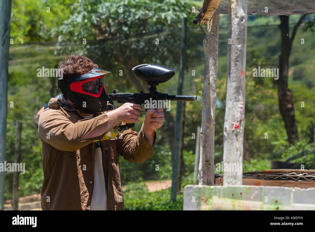 Paintball game action arena player gun in old broken house outdoors countryside arena. Stock Photo