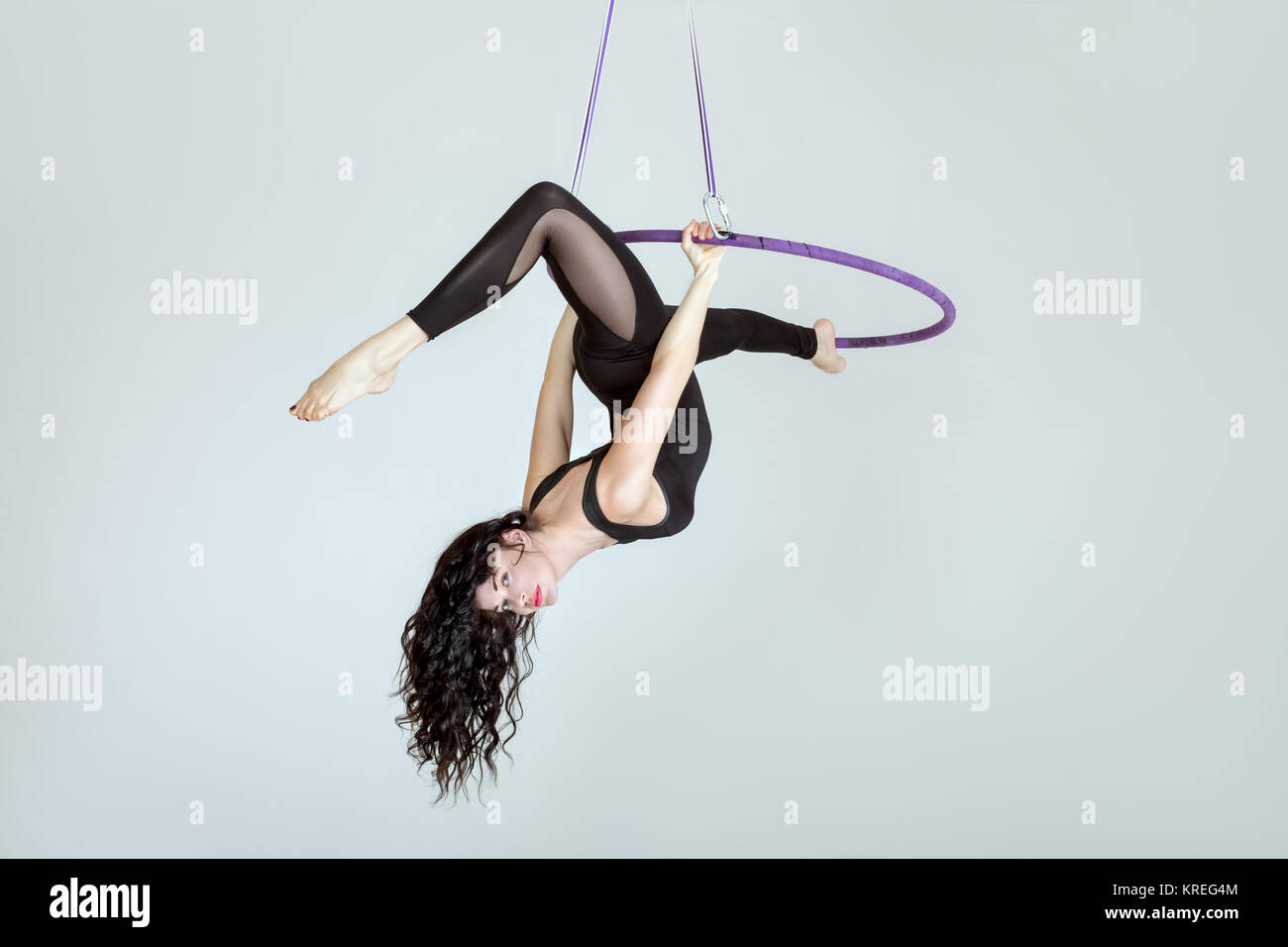 Woman acrobat on a hula hoop does tricks. Stock Photo
