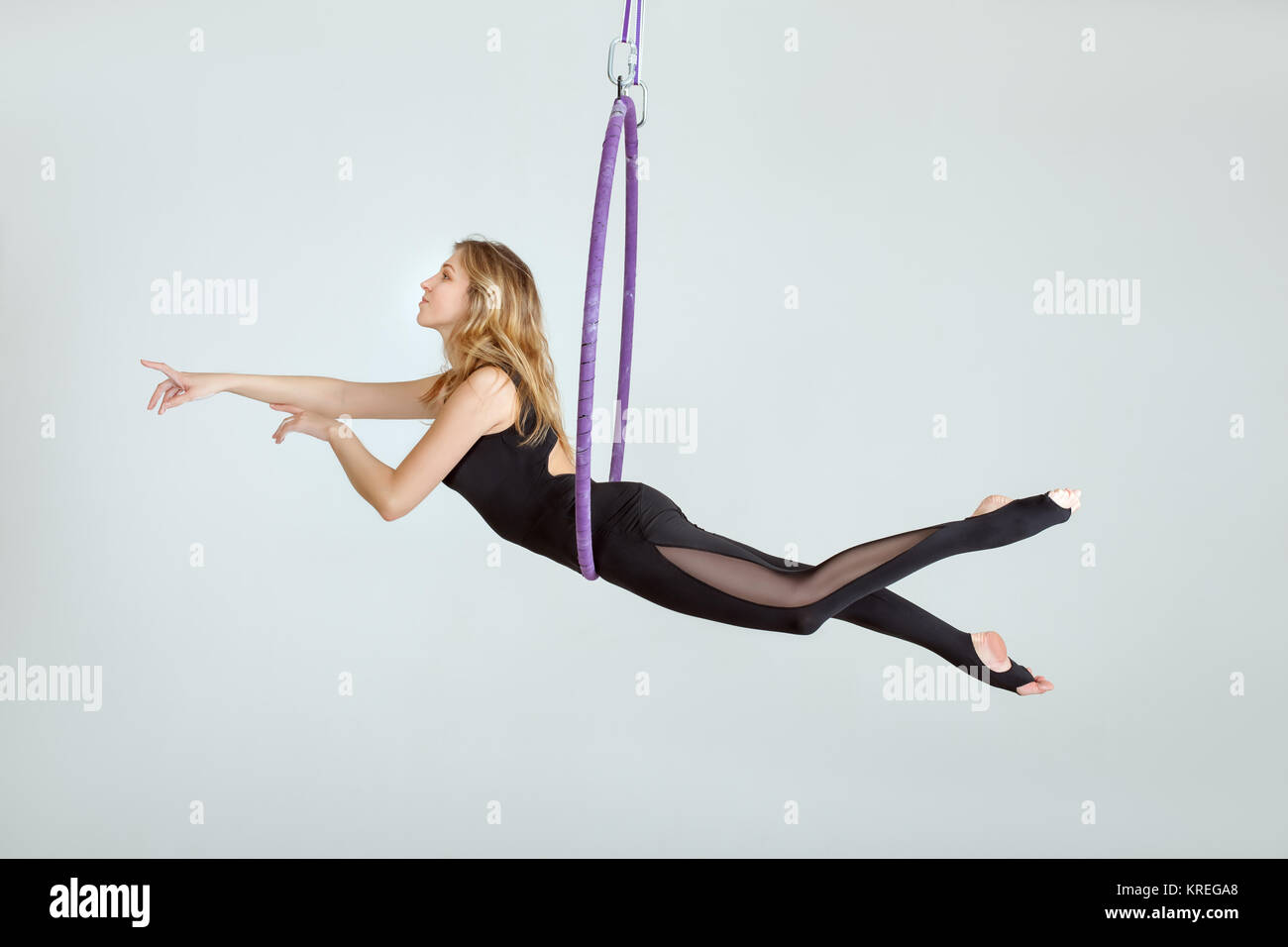 The acrobat has hung on a hula hoopa, she performs a dance at a height. Stock Photo