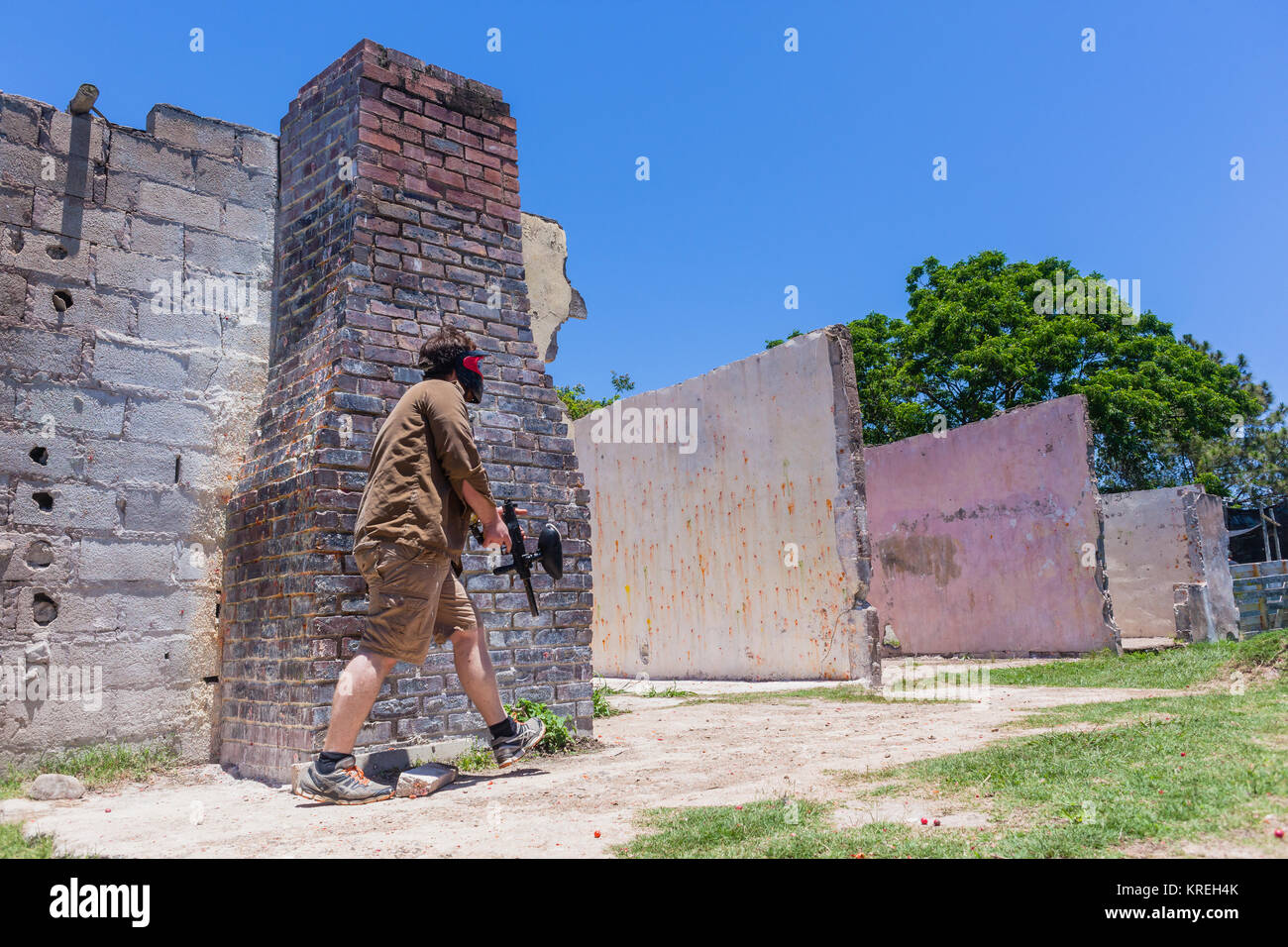 Paintball game arena player gun in old broken house wall with pelet