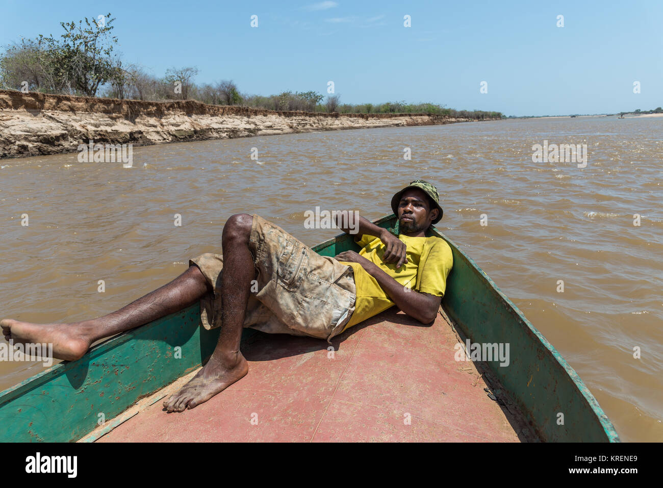 A Malagasy man lay on the bow of a ferry boat on Mania River. Madagascar, Africa. Stock Photo