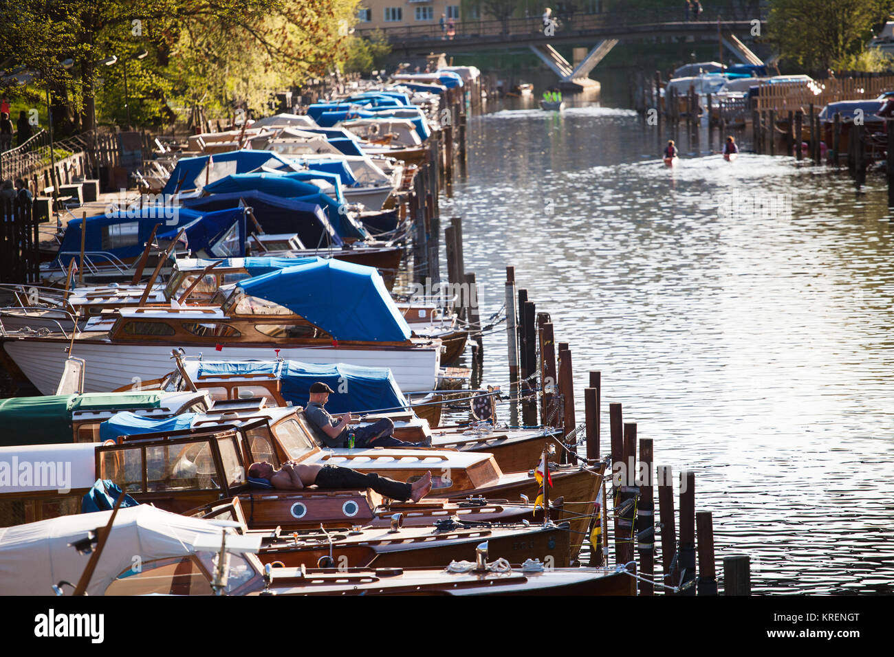 Boat owners sunbake and enjoys the evening sun, Långholmen canal, Stockholm Stock Photo