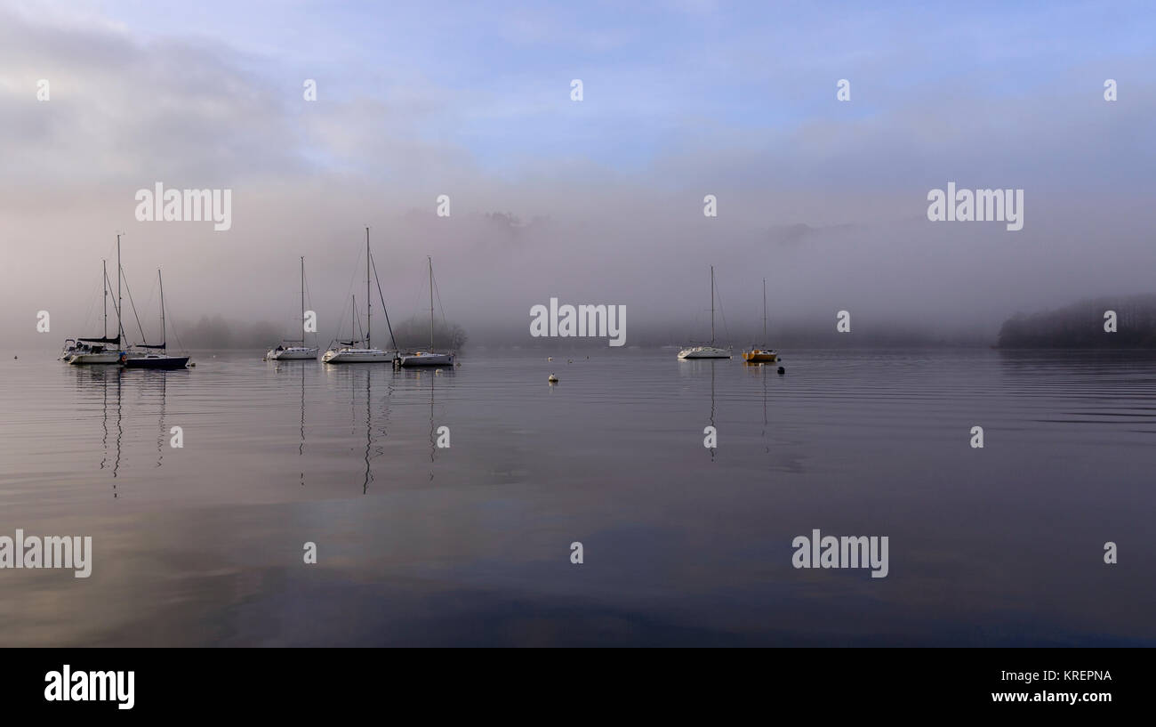 Boats on Windermere as the sun starts to lift the early morning mist