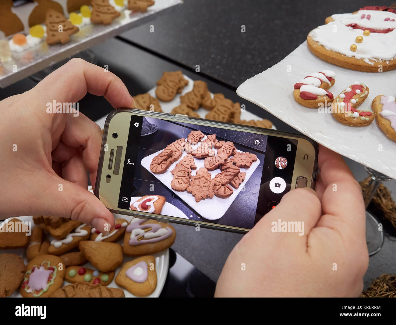 Woman taking a picture of digestive biscuits and gingerbread with a smartphone Stock Photo