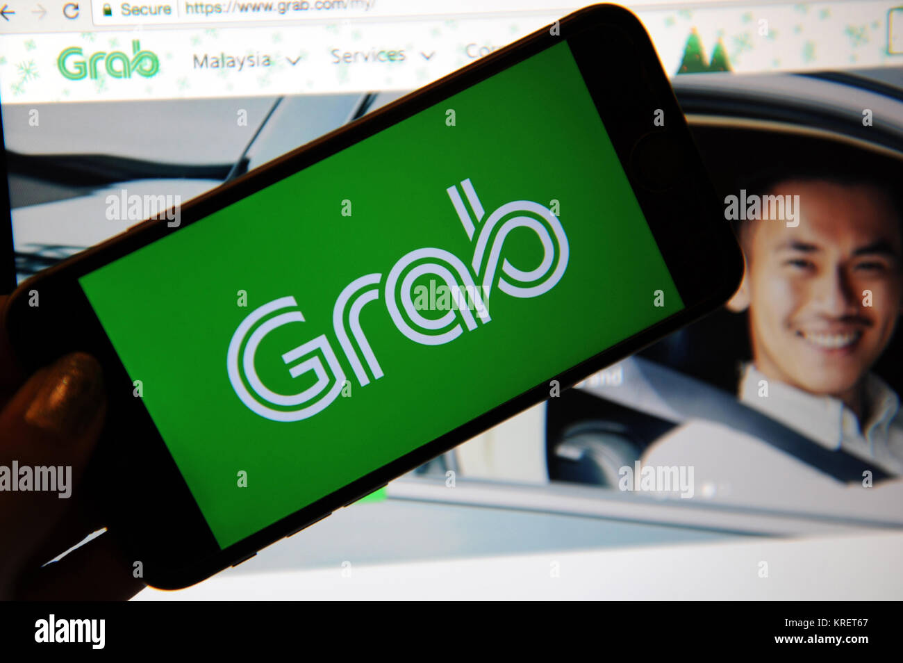 Grab, the ride hailing company logo on a phone and website on a