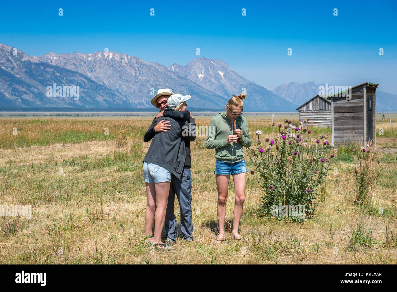 A man hugs a woman lovely while a girl plays a recorder in Jackson Hole, Grand Tetons National Park, Teton County, Wyoming Stock Photo