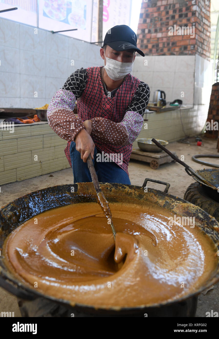 Nanning, China's Guangxi Zhuang Autonomous Region. 19th Dec, 2017. A villager stirs the sugar syrup to make brown sugar at Fuliang Village of Fucheng Township in Nanning, capital of south China's Guangxi Zhuang Autonomous Region, Dec. 19, 2017. The handmade Fucheng brown sugar, enlisted as an intangible cultural heritage in Nanning, has a history of more than a century. Credit: Lu Bo'an/Xinhua/Alamy Live News Stock Photo