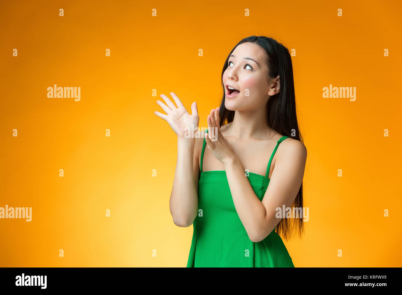 The surprised Chinese girl on yellow background Stock Photo