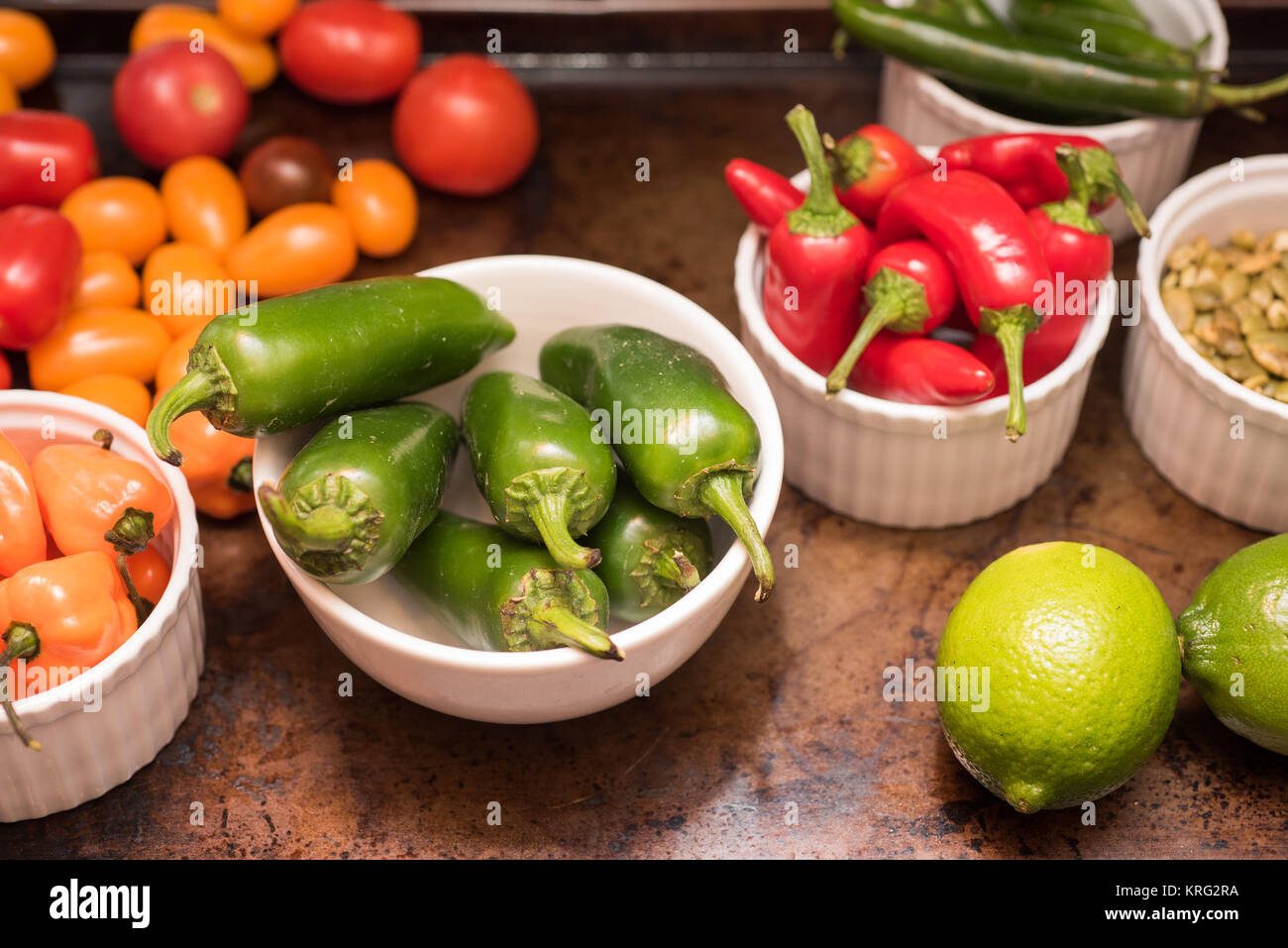 Selection of chilis, tomatoes and limes in bowls Stock Photo