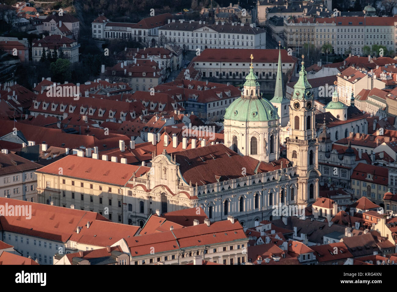 St. Nicolas church and roofs of Prague illuminated with the last rays of setting Sun Stock Photo