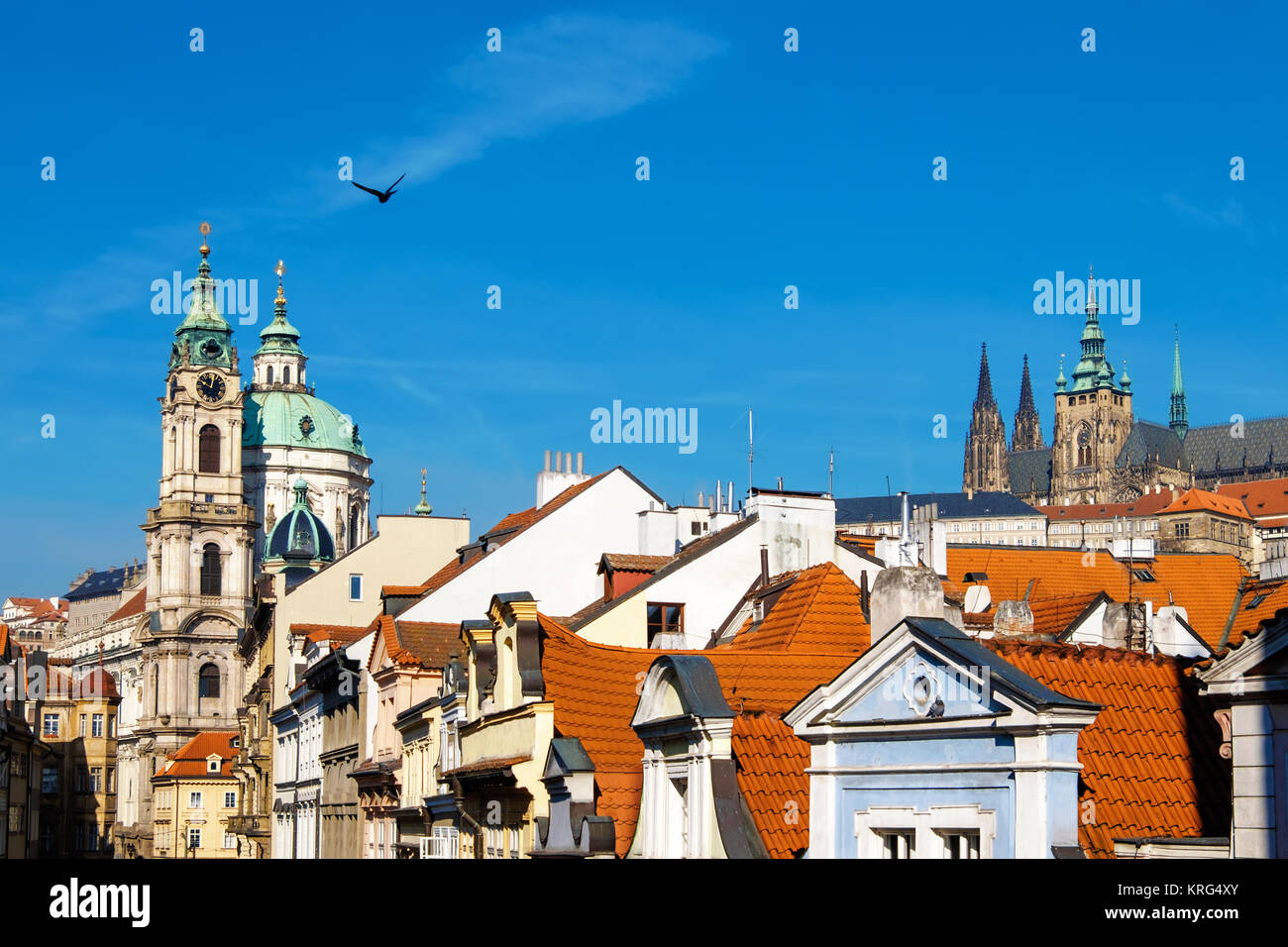 Prague, St. Nicolas church, St. Vitus Cathedral and and orange tiled roofs on a bright day. Space for your text on the sky. Stock Photo