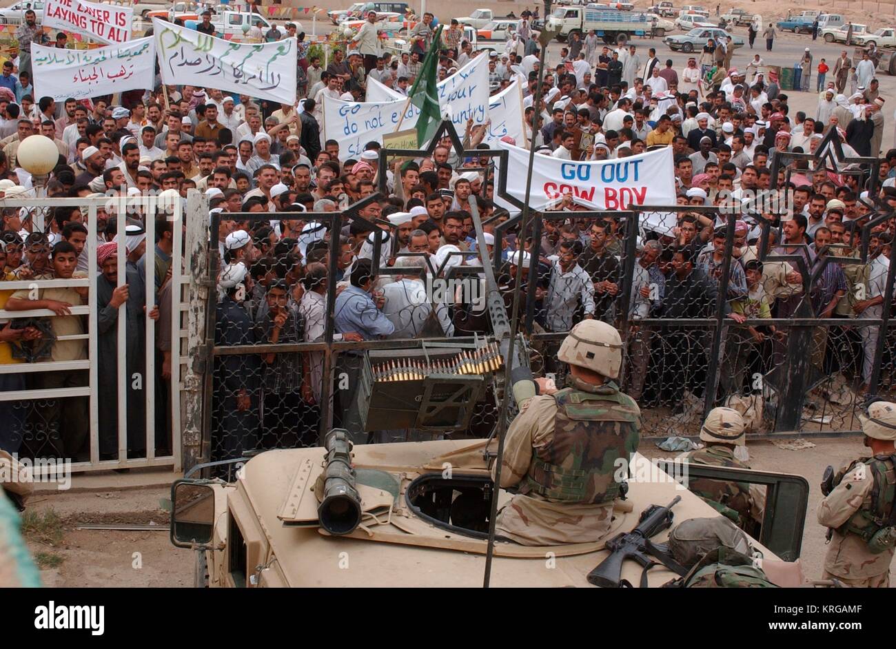 U.S. soldiers watch from atop tank guard posts as Iraqi civilians protest U.S. Army presence and demand the USA leaves Iraq following the liberation April 27, 2003 in Samarra, Iraq. Stock Photo