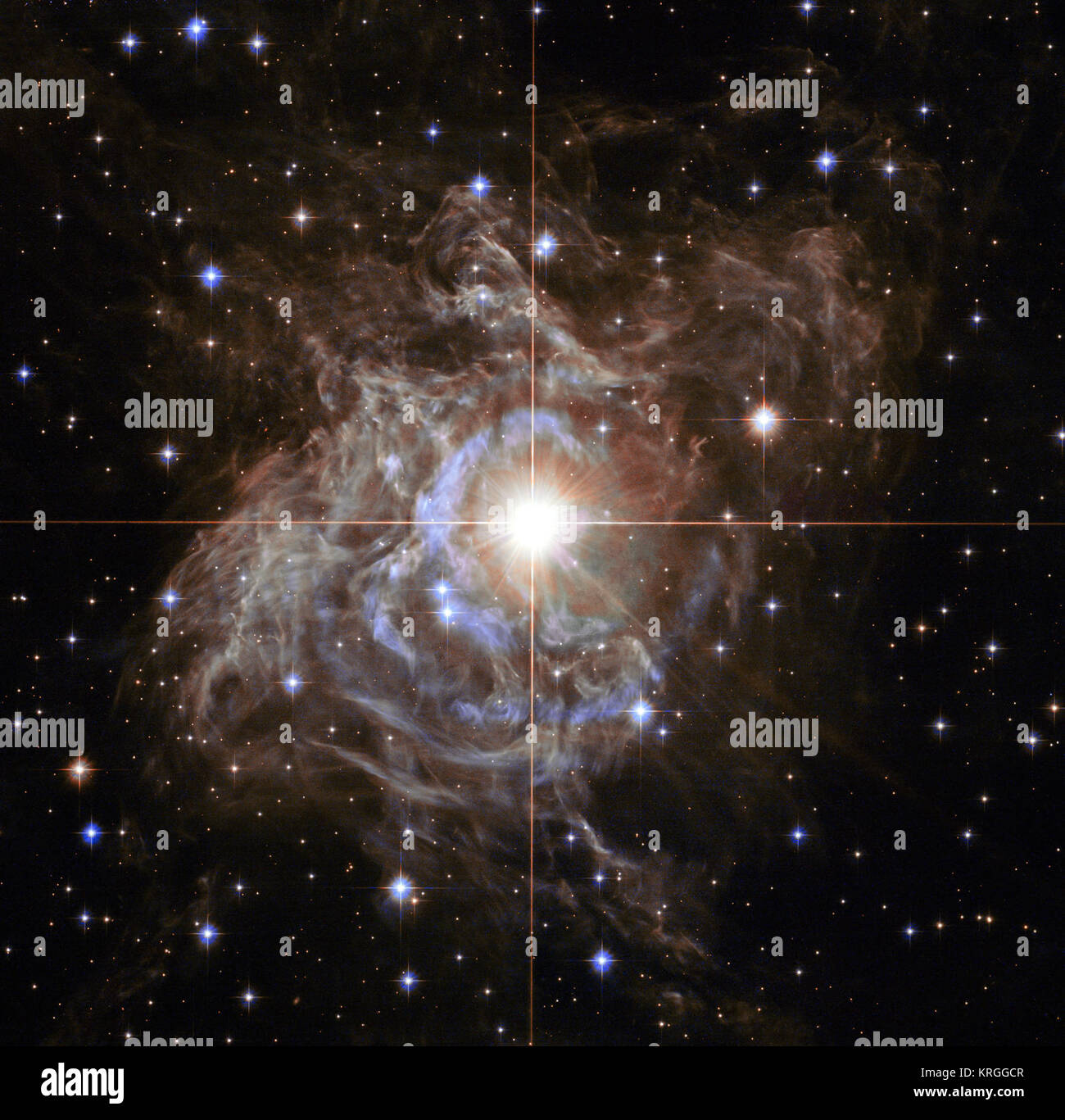 This Hubble image shows RS Puppis, a type of variable star known as a Cepheid variable. As variable stars go, Cepheids have comparatively long periods — RS Puppis, for example, varies in brightness by almost a factor of five every 40 or so days. RS Puppis is unusual; this variable star is shrouded by thick, dark clouds of dust enabling a phenomenon known as a light echo to be shown with stunning clarity. These Hubble observations show the ethereal object embedded in its dusty environment, set against a dark sky filled with background galaxies. Heic1323a -1243686232 Stock Photo