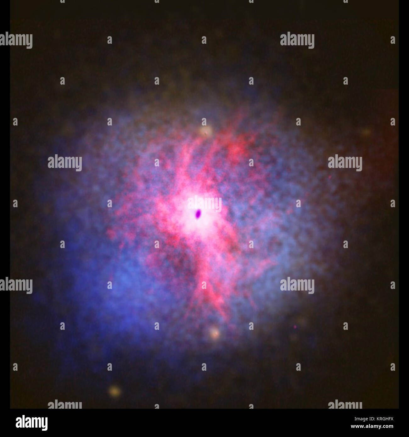 This image shows a composite view of the giant elliptical galaxy NGC 5044.  The stellar component, as observed at optical wavelengths, is shown in white at the centre of the image. The other stars scattered around the image are foreground stars from our own Galaxy.  The galaxy is embedded in a hot atmosphere of ionised hydrogen gas, which is shown in blue. With temperatures up to tens of millions of K, the hot gas shines brightly in X-rays and was observed using NASA's Chandra X-ray Observatory.  Observations show that some of the hot gas cools down and flows towards the centre of the galaxy.  Stock Photo