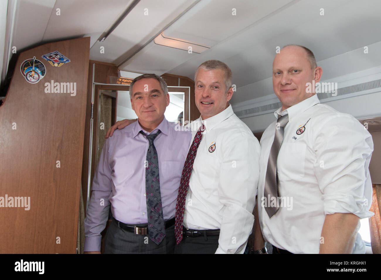Flying from their training base in Star City, Russia to their launch site at the Baikonur Cosmodrome in Kazakhstan, Expedition 39/40 Soyuz Commander Alexander Skvortsov of the Russian Federal Space Agency (Roscosmos; left), Flight Engineer Steve Swanson of NASA (center) and Flight Engineer Oleg Artemyev of Roscosmos (right) pose for pictures March 13 next to the wall of the plane bearing a newly applied sticker with  their mission insignia. Swanson, Artemyev and Skvortsov are preparing for their launch to the International Space Station March 26, Kazakh time, in their Soyuz TMA-12M spacecraft  Stock Photo