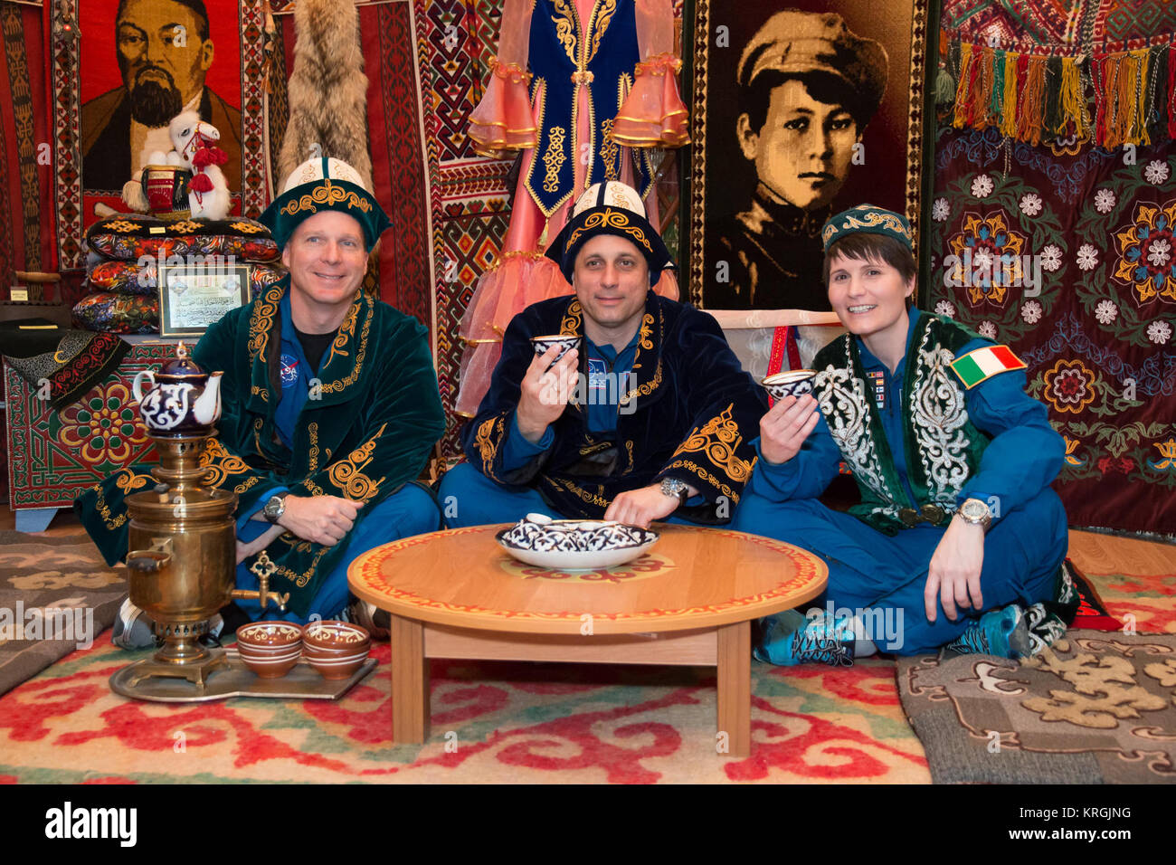 13-43-56-2:  In the town of Baikonur, Kazakhstan, Expedition 40/41 backup crewmembers Terry Virts of NASA (left), Anton Shkaplerov of the Russian Federal Space Agency (Roscosmos, center) and Samantha Cristoforetti of the European Space Agency (right) partake in a traditional Kazakh ceremony May 17 in a “yurt”, or tent, during a tour of the community. The trio is backing up the prime crew, Flight Engineer Alexander Gerst of the European Space Agency, Soyuz Commander Max Suraev of the Russian Federal Space Agency (Roscosmos) and NASA Flight Engineer Reid Wiseman, who will launch from Baikonur on Stock Photo