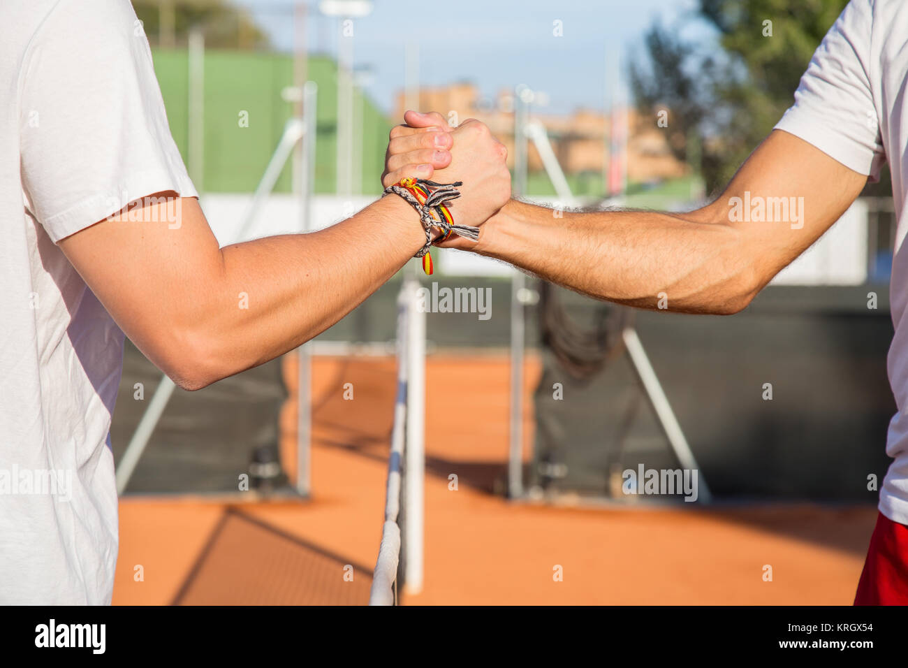 Close up of two professional tennis players holding hands over tennis