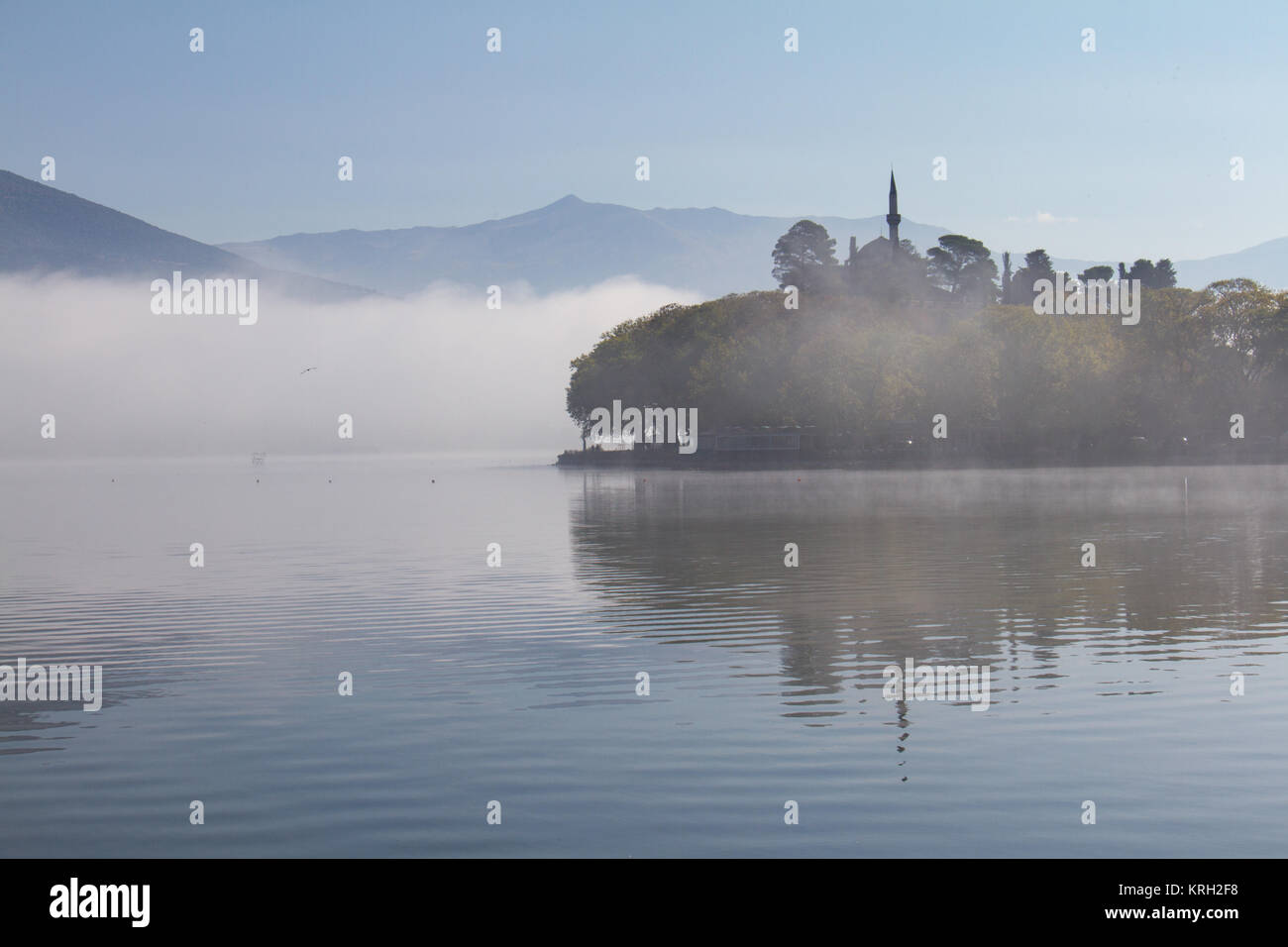 Atmospheric scene of Lake Pamvotis on a misty morning in Ioannina, Greece, with Aslan Pasha mosque in the background Stock Photo