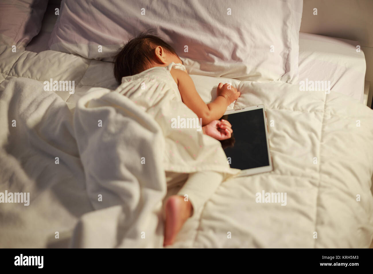 baby sleeping on bed after playing digital tablet Stock Photo