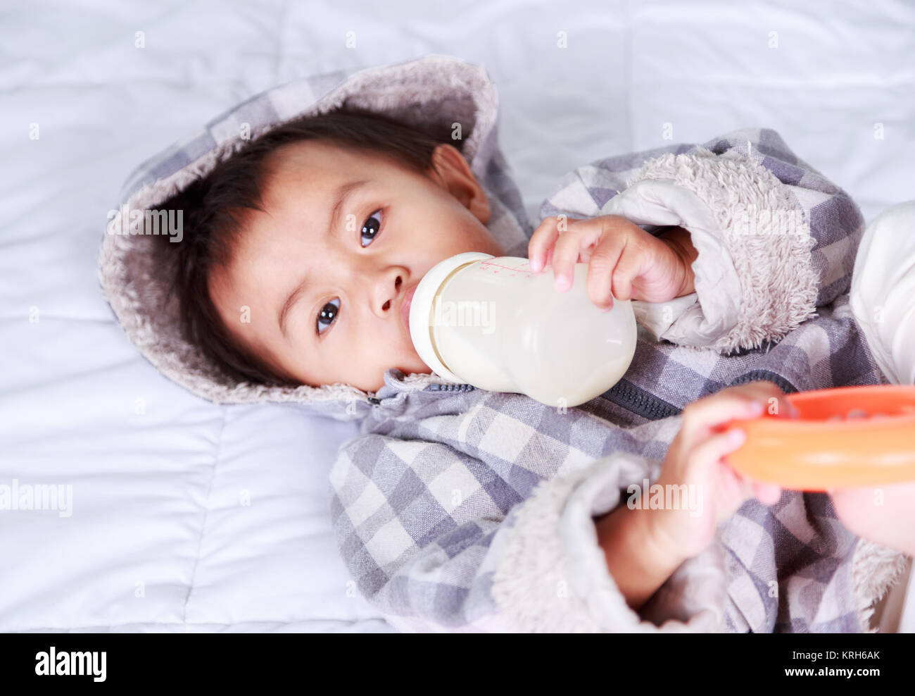baby drinking milk with bottle on bed at home Stock Photo Alamy