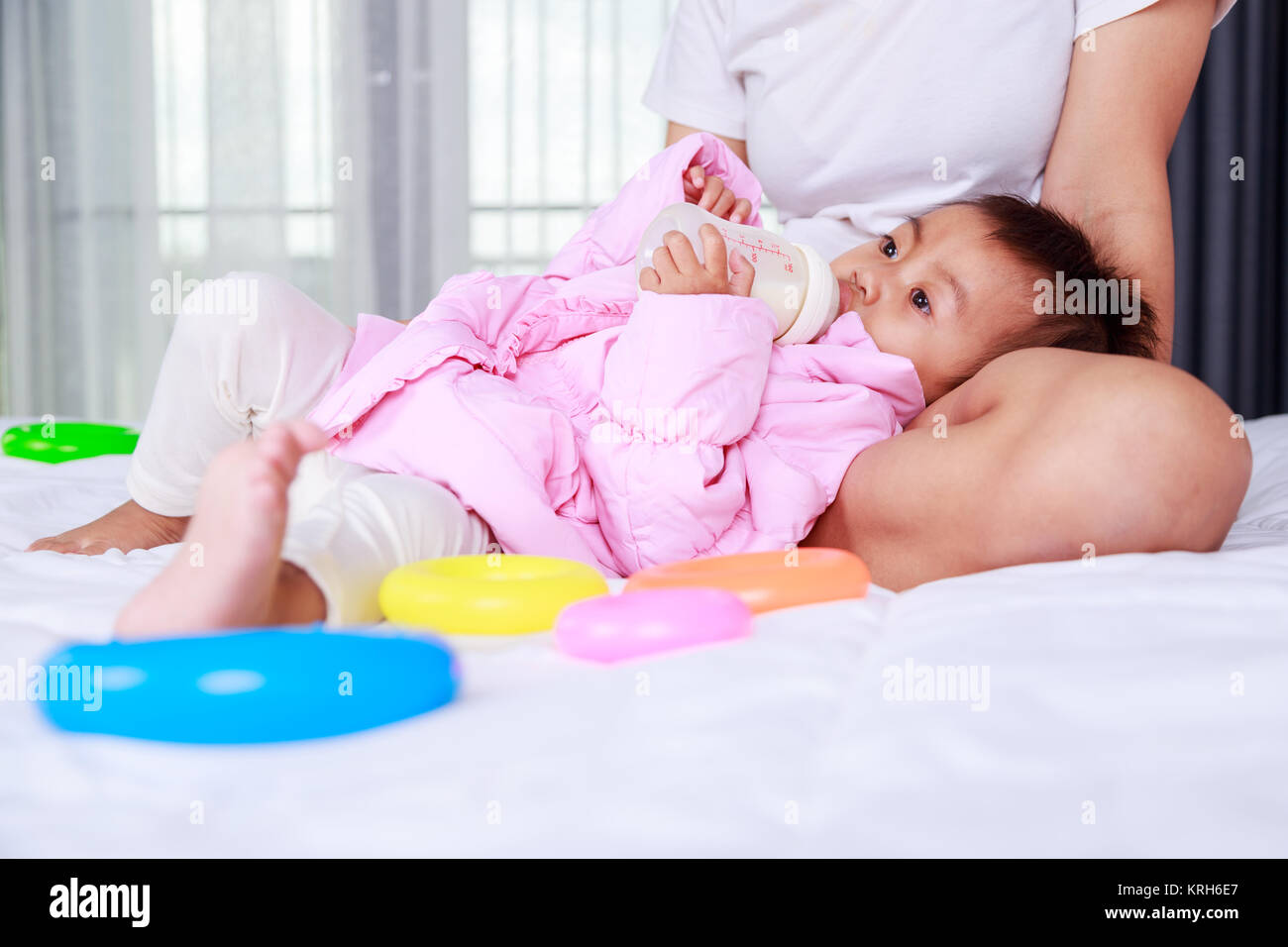 girl drinking bottle of milk laying on bed blond toddler Stock Photo - Alamy