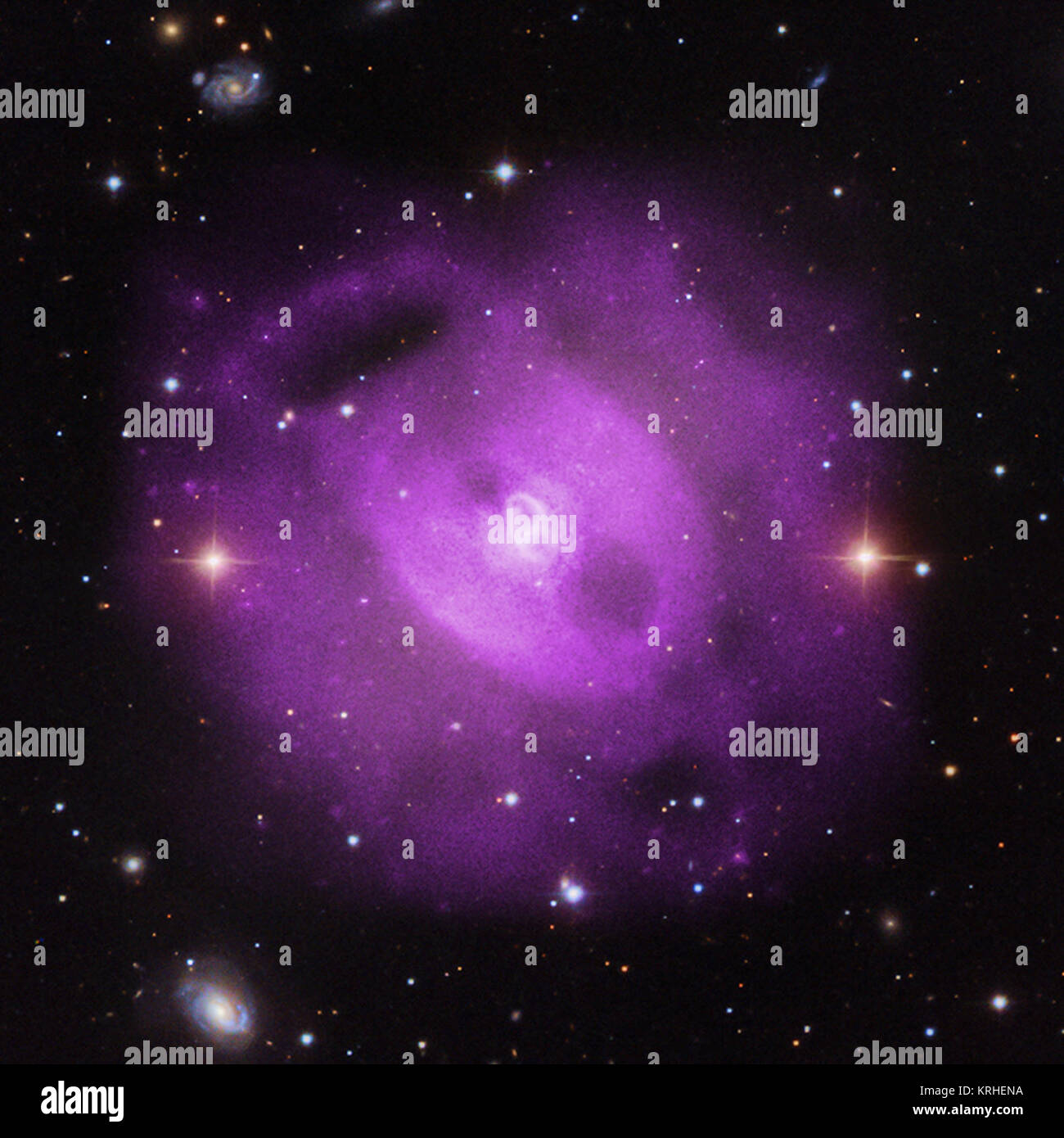 Astronomers have used NASA's Chandra X-ray Observatory to show that a supermassive black hole at the center of a group of galaxies has erupted multiple times over a period lasting about 50 million years. Evidence for the eruptions can be found in the cavities, or bubbles, carved out of the hot gas that envelops the galaxies and glows in X-rays. This composite image contains the X-rays from Chandra (pink) that have been combined with visible light data (gold). Ngc5813 composite Stock Photo