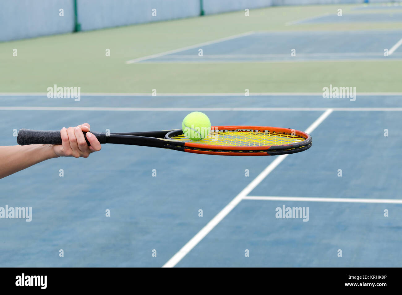 Concept of sport and active lifestyle tennis court, hand holds tennis racket with ball Stock