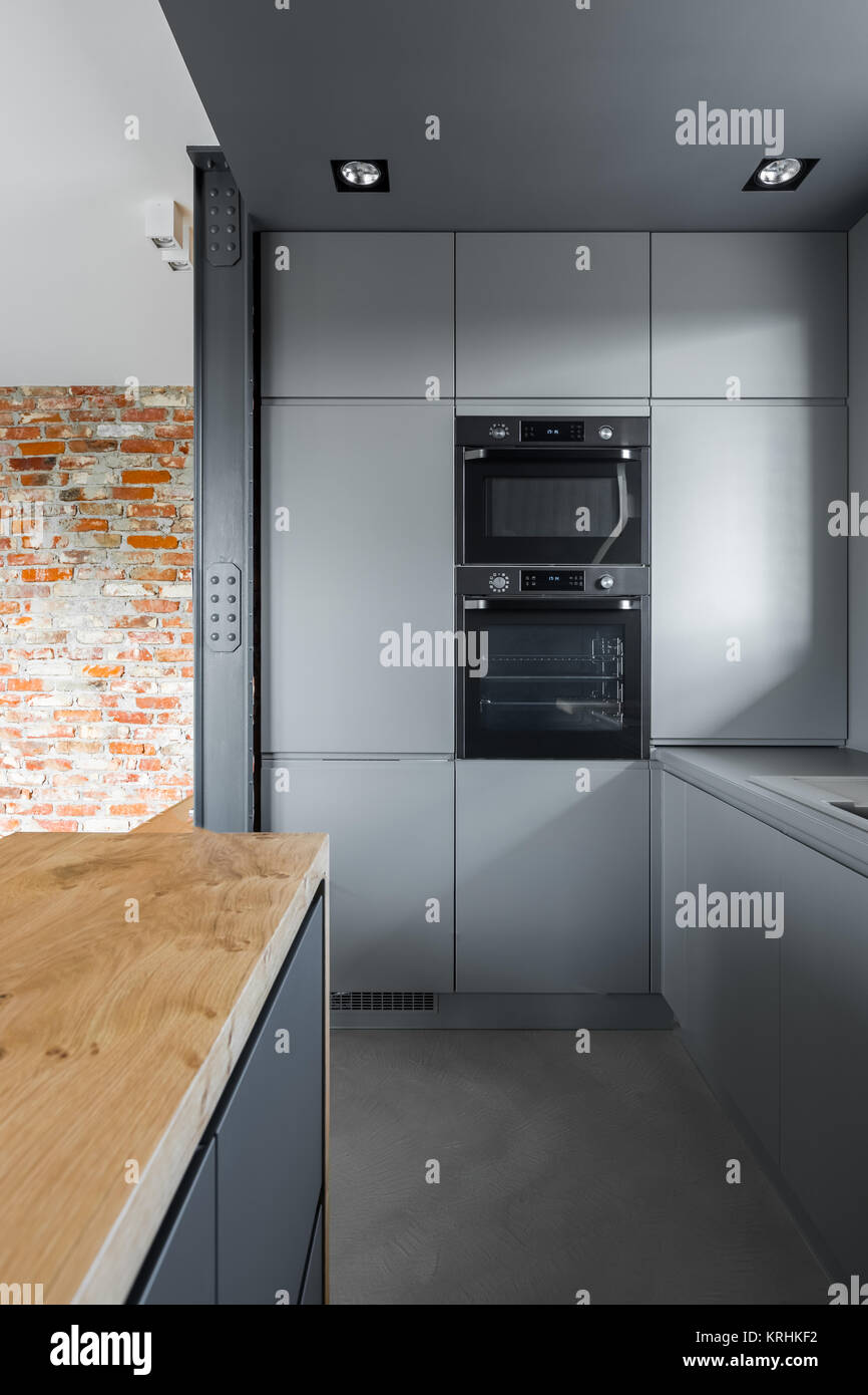 Gray kitchen wall with built-in oven and microwave Stock Photo