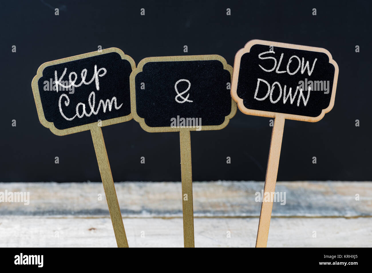 Keep Calm and Slow Down message written with chalk on mini blackboard labels Stock Photo