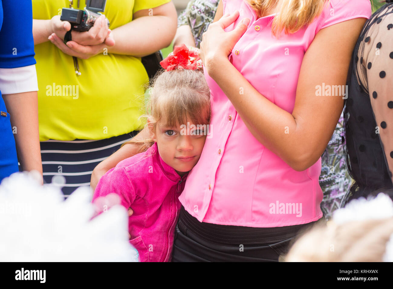 Five-year girl standing in the crowd and clung to her mother Stock Photo