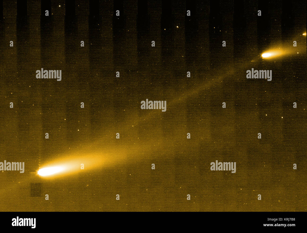 This image from NASA's Spitzer Space Telescope shows three of the many fragments making up Comet 73P/Schwassman-Wachmann 3. The infrared picture also provides the best look yet at the crumbling comet's trail of debris, seen here as a bridge connecting the larger fragments.  The comet circles around our sun every 5.4 years. In 1995, it splintered apart into four pieces, labeled A through D, with C being the biggest. Since then, the comet has continued to fracture into dozens of additional pieces. This image is centered about midway between fragments C and B; fragment G can be seen in the upper  Stock Photo
