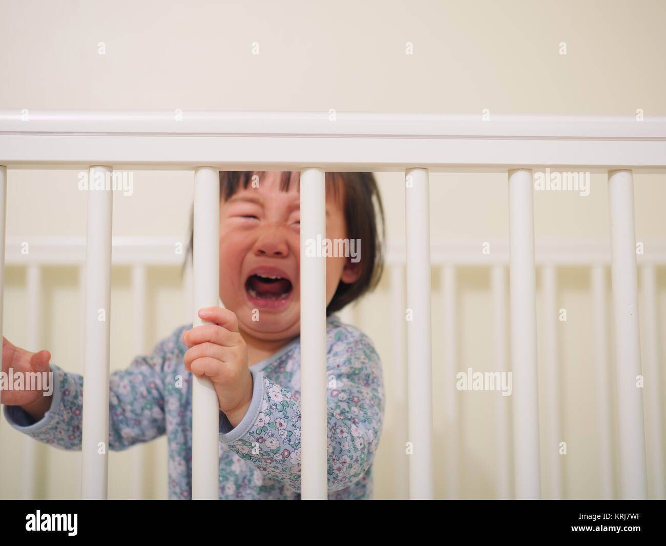 Crying Baby girl in cot bed Stock Photo Alamy