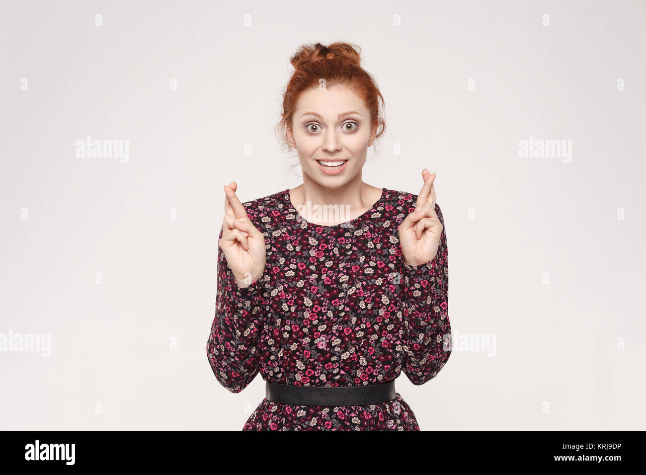 Human emotions and feelings. Superstitious teenager ginger woman crossing fingers for good luck, hoping her wishes will come true, having excited happ Stock Photo