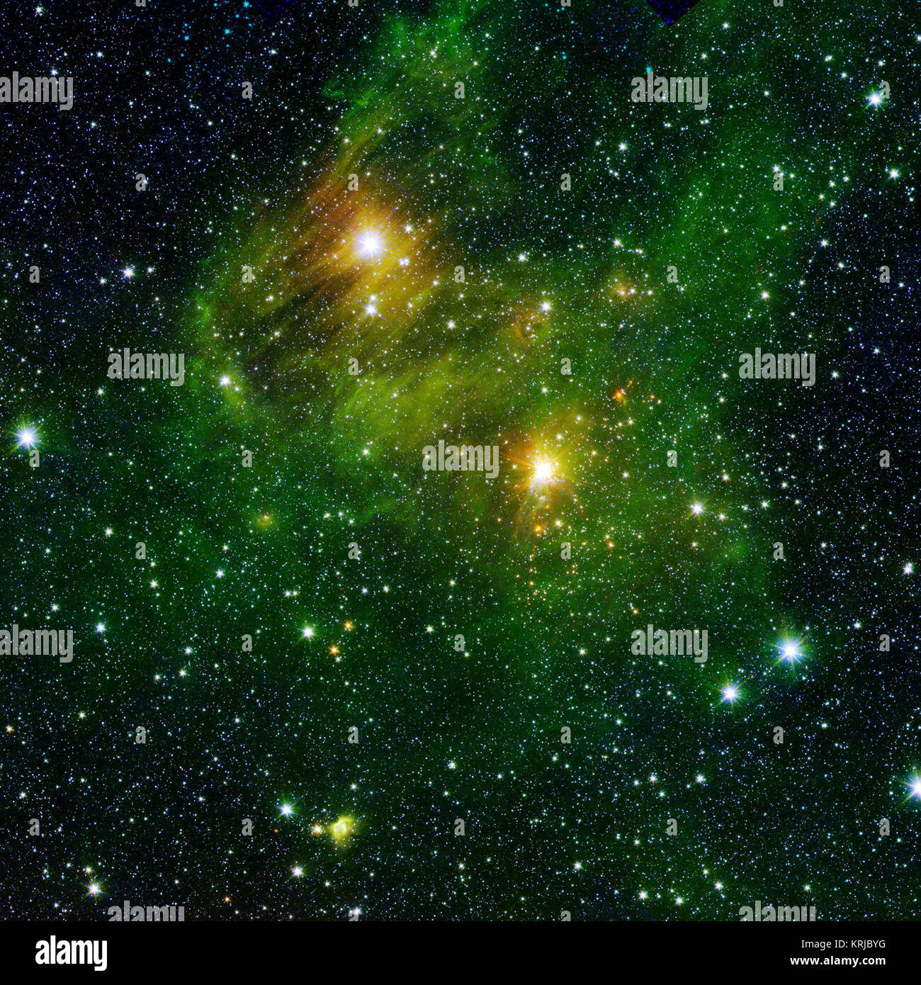 Two extremely bright stars illuminate a greenish mist in this and other images from the new GLIMPSE360 survey. This fog is comprised of hydrogen and carbon compounds called polycyclic aromatic hydrocarbons (PAHs), which are found right here on Earth in sooty vehicle exhaust and on charred grills. In space, PAHs form in the dark clouds that give rise to stars. These molecules provide astronomers a way to visualize the peripheries of gas clouds and study their structures in great detail. PAHs are not actually "green;" a representative color coding in these images lets scientists observe PAHs glo Stock Photo
