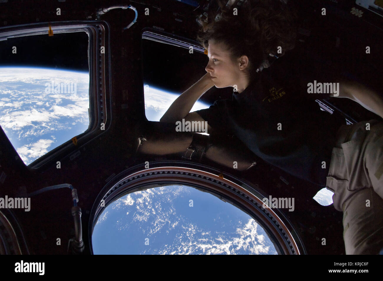 ISS024-E-014263 (11 Sept. 2010) --- NASA astronaut Tracy Caldwell Dyson, Expedition 24 flight engineer, looks through a window in the Cupola of the International Space Station. A blue and white part of Earth and the blackness of space are visible through the windows. Tracy Caldwell Dyson in Cupola ISS Stock Photo