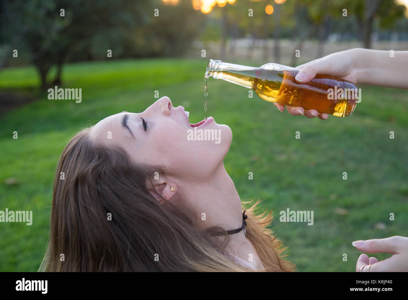 Young woman giving beer to her friend from a bottle Stock Photo Alamy