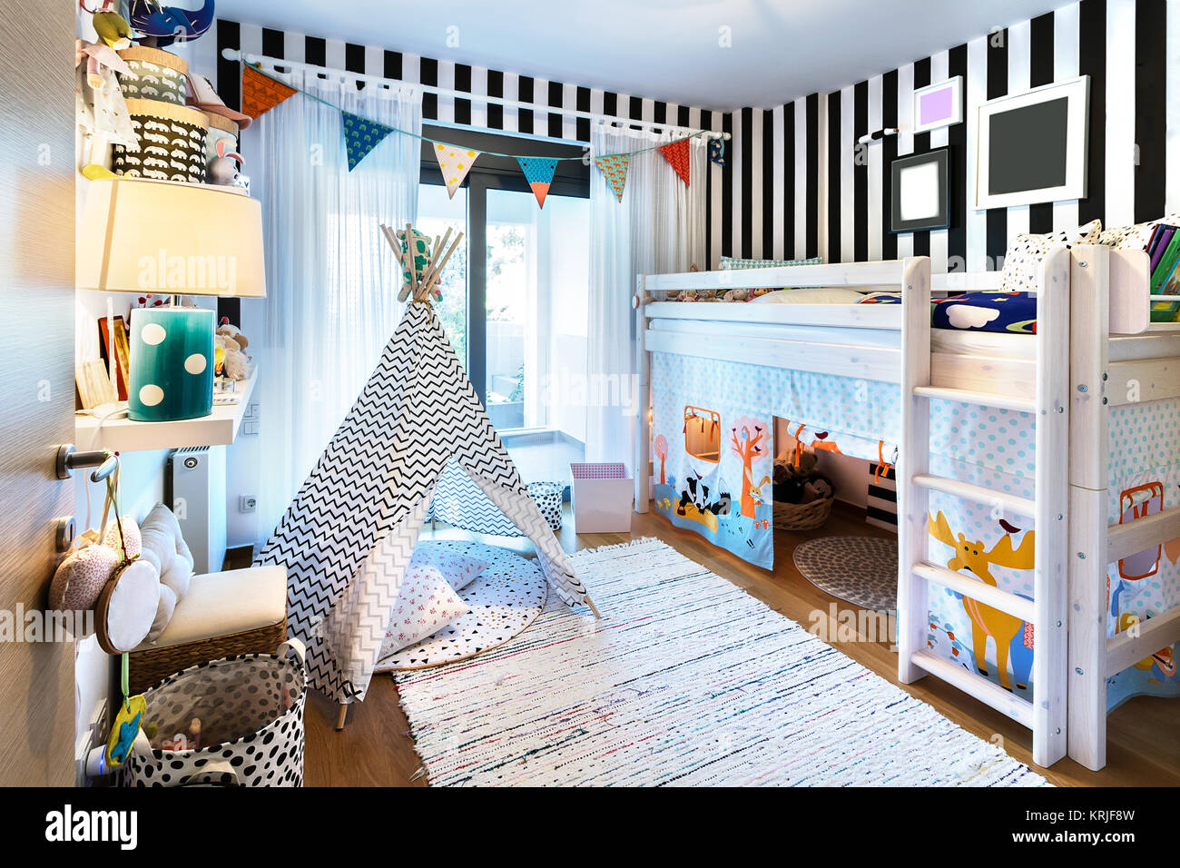 Kids bedroom  with bunk wooden bed, teepee, stands, carpet frames and toys. Stock Photo