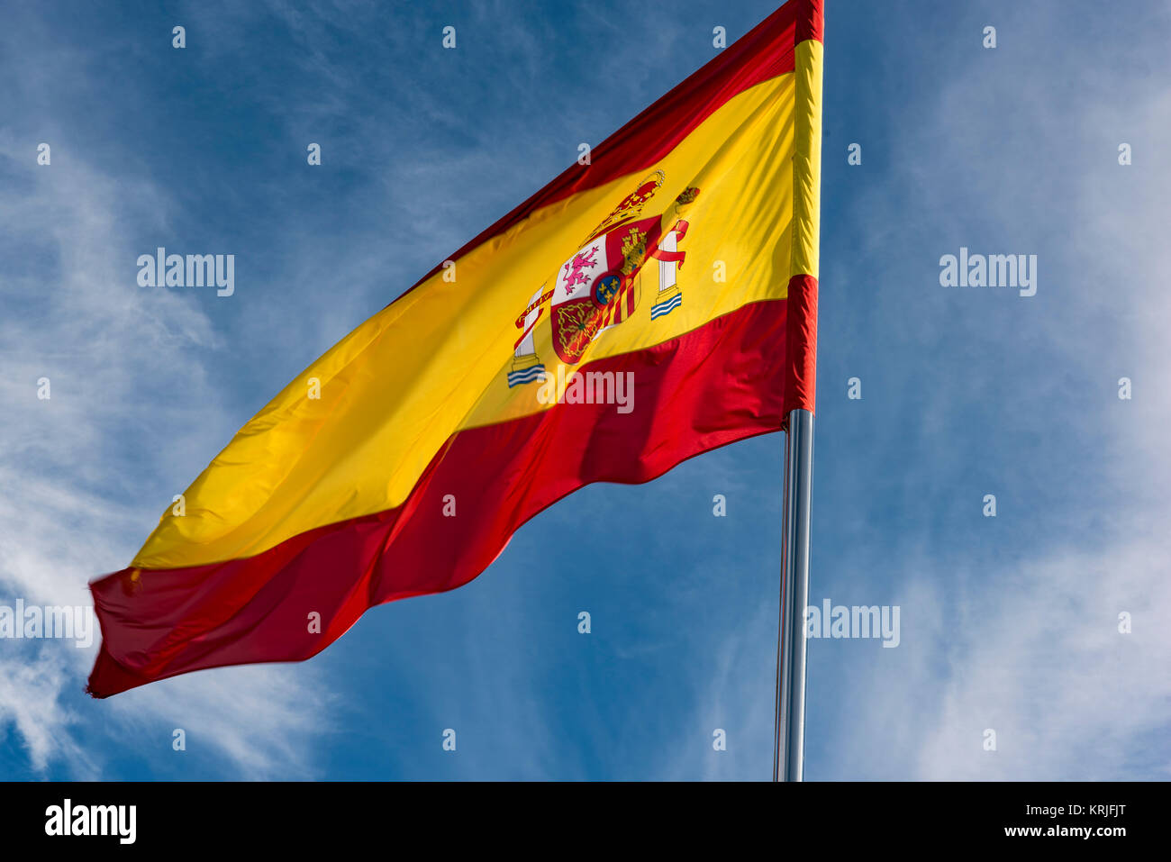 Spanish Flag Showing the Crown  Flies in front of a Blue Sky with With Clouds Stock Photo